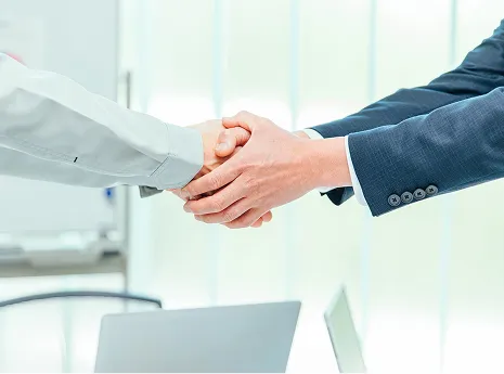 スーツの男性と作業員の男性が握手をする手元